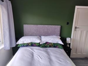 a bed with white pillows and a green wall at Parkdale-2 Bedroom House in Sheldon Birmingham in Birmingham