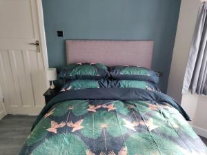 ein Schlafzimmer mit einem Bett mit grüner Bettdecke und Kissen in der Unterkunft Parkdale-2 Bedroom House in Sheldon Birmingham in Birmingham + 53 Fotos