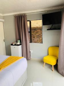 a bedroom with a bed and a yellow chair at LINGAS inn in Richards Bay