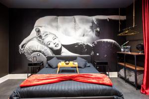 a bedroom with a bed with a painting on the wall at Hollywood Night-Jacuzzi & Private Movie Theater in Mulhouse