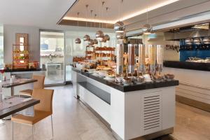 a restaurant with a counter with food on it at Ramada Hotel & Suites by Wyndham Izmir Kemalpasa in Kemalpaşa