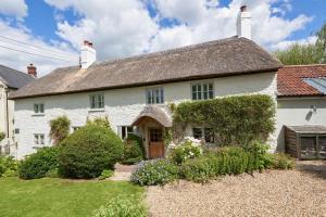 a white house with a garden in front of it at Palmers Cottage in Dalwood