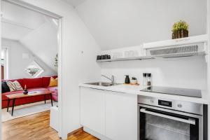a white kitchen with a sink and a stove at Studio By The Bridge in Tromsø