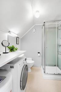 a white bathroom with a shower and a washing machine at Studio By The Bridge in Tromsø
