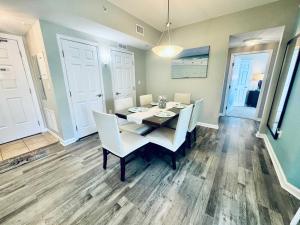a dining room with a table and white chairs at A Wave From it All in Destin