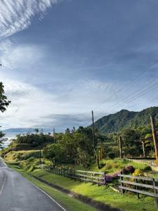 an empty road with a fence and mountains in the background at Rainforest Yasmin Hotel in Santa Fé