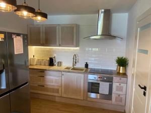 a kitchen with wooden cabinets and a stainless steel refrigerator at Domek Anastazja na Kaszubach z własną linią brzegową oraz balią in Borzyszkowo