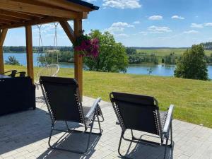 two chairs on a patio with a view of a lake at Domek Anastazja na Kaszubach z własną linią brzegową oraz balią in Borzyszkowo