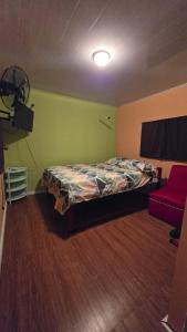 a bedroom with a bed and a red couch at CocoRelax in Siquirres +4 photos