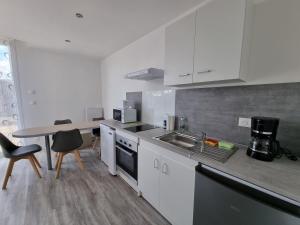 a kitchen with white cabinets and a table with chairs at Évasion Relaxante 4 personnes Spa, sauna et calme 