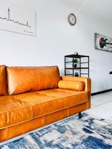 SandtonにあるLonehill Luxury Apartmentのリビングルーム(ブラウンレザーのソファ、時計付)