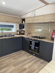 a kitchen with wooden cabinets and a stove top oven at Chrystall Caravan Tattershall Lakes in Tattershall