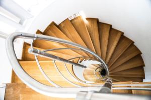 a spiral wooden staircase with a metal hand rail at Viva B&B in Anavyssos