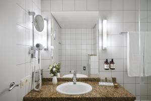 ein Badezimmer mit Waschbecken und Spiegel in der Unterkunft NH Leipzig Messe in Leipzig