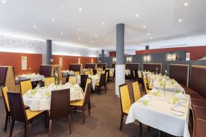ein Esszimmer mit weißen Tischen und Stühlen in der Unterkunft NH Leipzig Messe in Leipzig