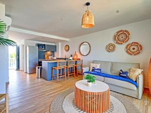 a living room with a couch and a table at Duplex 2 chambres Baie Orientale, piscine, clim, WiFi - FR-1-734-41 in Orient Bay