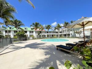 a swimming pool with two lounge chairs and an umbrella at Duplex 2 chambres Baie Orientale, piscine, clim, WiFi - FR-1-734-41 in Orient Bay