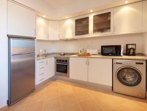 a kitchen with white cabinets and a stainless steel refrigerator at Aldeia Azul Resort in Lagos