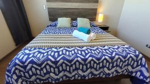 a blue and white bed with two pillows on it at Oceana Suites Concepto One in Calama
