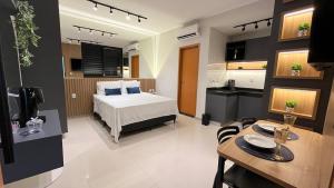a bedroom with a bed and a table and a kitchen at Anápolis / Suíte Cid. Universitária in Anápolis