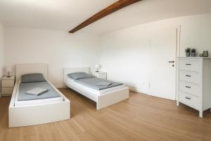two beds in a room with white walls and wood floors at Moderne Ferienwohnung Klosterblick in Guxhagen
