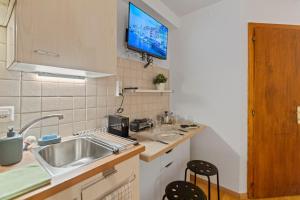 Crans-Montana - Studio centre 2 pers - Rue du Prado في Lens: مطبخ مع حوض وتلفزيون على الحائط