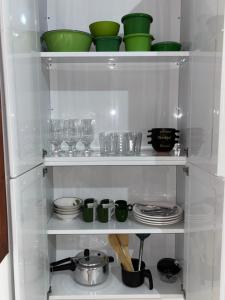 a refrigerator filled with dishes and green bowls and plates at Casa Viturino in Tailandia