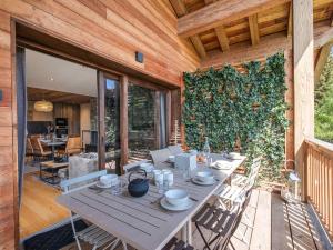 a table and chairs on a patio with a green wall at Appartement avec Sauna et Jacuzzi aux Saisies - FR-1-809-14 in Les Saisies