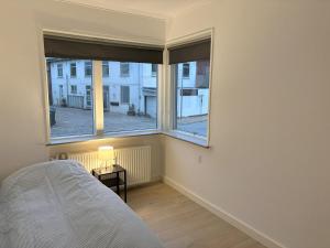 a bedroom with a bed and two large windows at Bright and spacious 3 bedroom with balcony close to the city in Aabenraa
