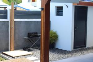 a tiny house with a black door next to a fence at Kaza Kigélia - Villa avec piscine privative - Proche de Tout in Grand-Bourg