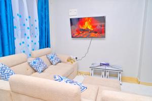 a living room with a couch and a fire on the wall at GILGAL Homes in Kisii