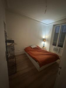 a bedroom with a bed with a orange comforter at New apartment rue de Fontenay in Vincennes +3 photos