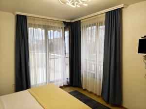 a bedroom with a bed and two large windows at Trend Apart in Burgas