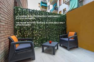 a patio with two chairs and a table and a hedge at SAN FELICE 135 - 2 in Bologna