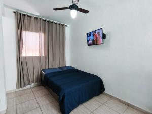 a bedroom with a blue bed and a ceiling fan at Kitnet no centro de Bertioga, ao lado do Rio de Pesca a 3 min da praia, da balsa e de pontos turísticos, com Wi-Fi, vaga e churrasqueira! in Bertioga