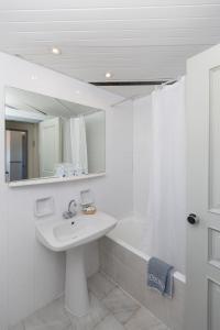 ein weißes Badezimmer mit einem Waschbecken und einer Badewanne in der Unterkunft Samaina Port Hotel in Karlovasi