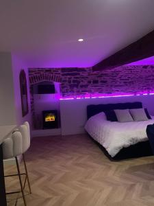 una camera da letto con illuminazione viola, un letto e un camino di Ombre et Douceur a Josselin