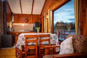 a kitchen with a table and chairs and a large window at Cabanas Palafitos Dalmacia in Castro