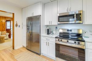 a kitchen with white cabinets and a stainless steel refrigerator at Cozy Cottage Just 2 Blocks From the River! in Colonial Beach