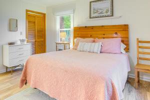 a bedroom with a pink bed with a wooden headboard at Cozy Cottage Just 2 Blocks From the River! in Colonial Beach