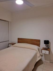 a bedroom with a bed and a white wall at Monoambiente en Mar del Plata in Mar del Plata