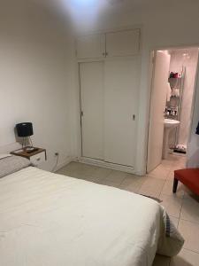 a bedroom with a white bed and a sliding door at Monoambiente en Mar del Plata in Mar del Plata