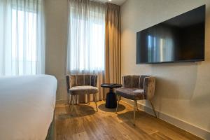a hotel room with two chairs and a flat screen tv at Eilandhotel Texel - Nieuw geopend hotel in De Cocksdorp