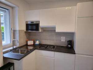 a kitchen with white cabinets and a sink and a microwave at Casa Perla in Gaeta