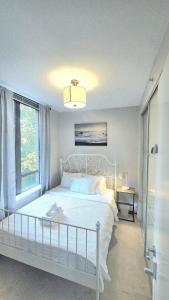 ノースバンクーバーにあるBright 2BR Close to Seabus, and Lower Lonsdaleの白いベッドと窓のある白い寝室
