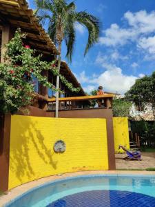 a man standing on a balcony next to a swimming pool at Bahia Outeiro das Brisas - Gibs' House in Porto Seguro