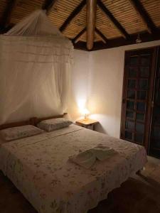 a bedroom with a bed and a table with a lamp at Bahia Outeiro das Brisas - Gibs' House in Porto Seguro