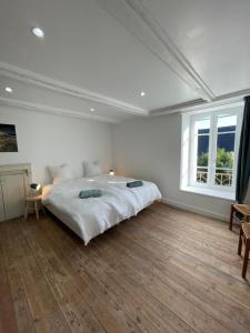 RospordenGrande maison 20 min plage, 14 personnes, 5 SDB, literie grand confort的一间带大床和窗户的白色卧室