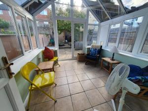 a conservatory with chairs and a room with windows at Cosy cottage in the centre of Dursley in Dursley +4 photos