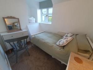 a bedroom with a bed and a mirror and a desk at Cosy cottage in the centre of Dursley in Dursley